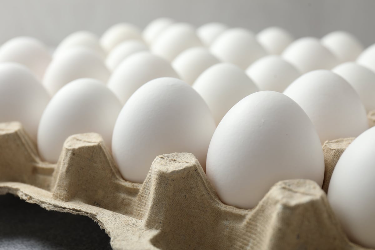 Raw chicken eggs in egg carton on table, closeup